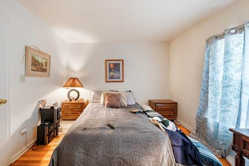 a bedroom with a bed and two dressers and a window