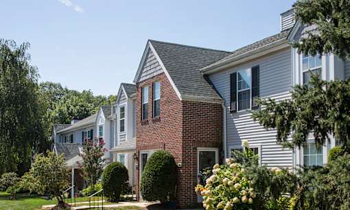 Exterior of Westridge Gardens with tall tress and beautiful bushes on a sunny day