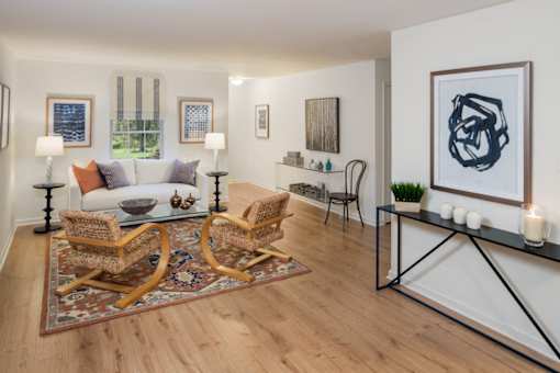 Furnished living room with a white couch and two wicker chairs sitting on top of an area rug