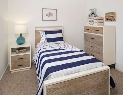 Bedroom with a twin size bed, nightstand, and a tall dresser.
