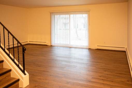 A room with wooden floors and a staircase leading to another floor.