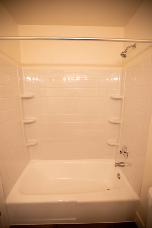 A white bathtub with a shower head above it.