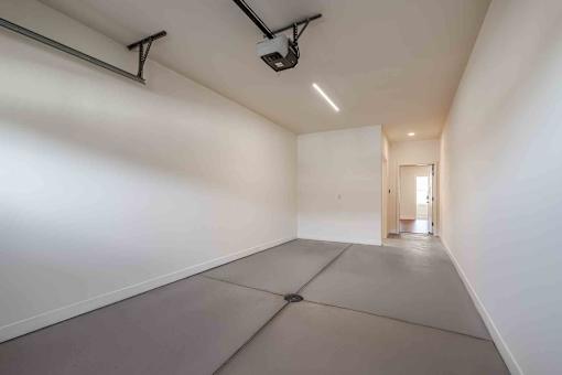 A long, empty hallway with a white wall and a grey floor.