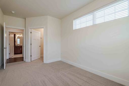 A room with a carpeted floor and two doors, one of which is open.