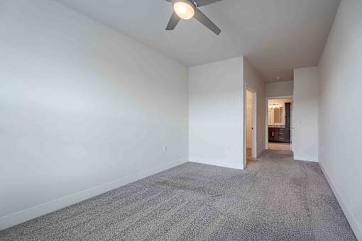 A room with a carpeted floor and a ceiling fan.