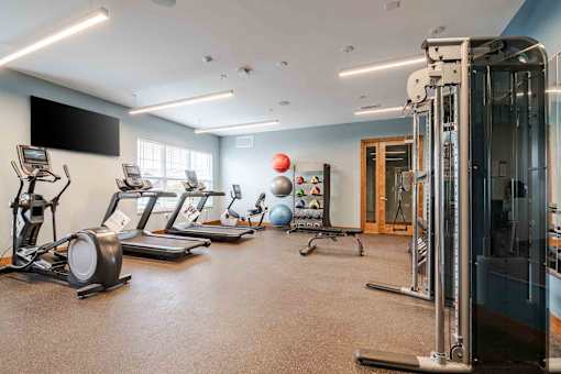 A spacious gym with a variety of equipment including treadmills, elliptical machines, and a weight machine.