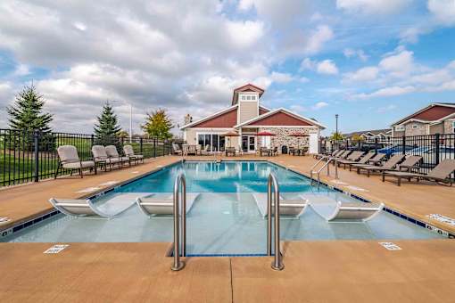 A large outdoor pool with a diving board and lounge chairs.