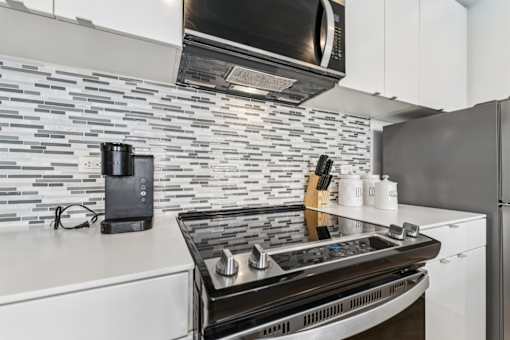 A modern kitchen with a black stove top oven and a black microwave above it.