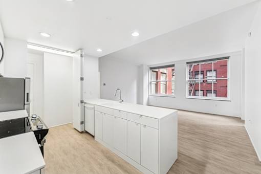 A kitchen with white cabinets and a wooden floor.