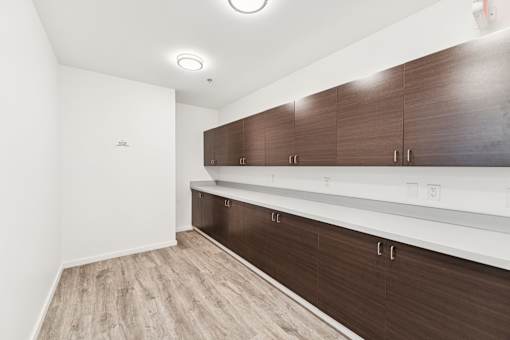 A room with brown and white cabinets and a light brown floor.
