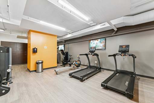 A gym with treadmills, a weight machine, and a TV.
