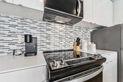 A modern kitchen with a black stove top oven and a black microwave above it.