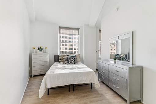 A bedroom with a bed, dresser, and mirror.