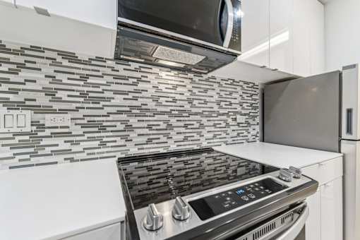 A modern kitchen with a stove top oven and microwave above it.