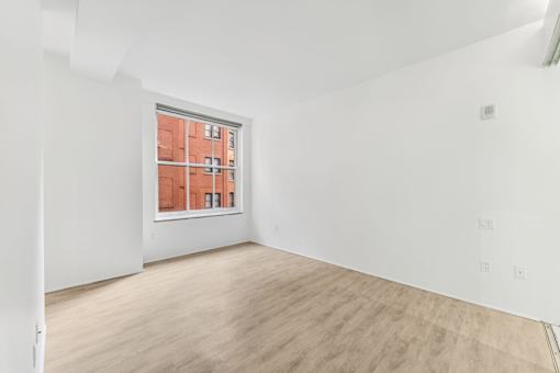 A room with a window showing a red building outside.