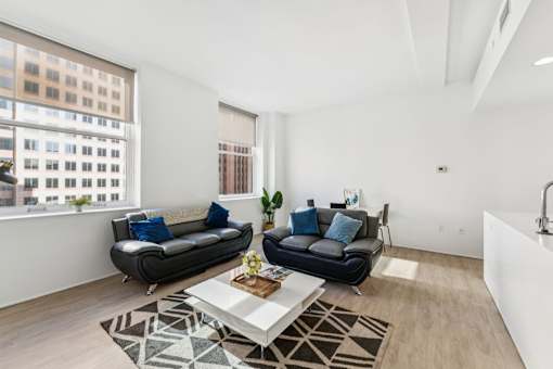 A living room with two black leather sofas and a coffee table in front of a large window.