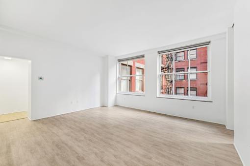 A room with a window showing a red building outside.