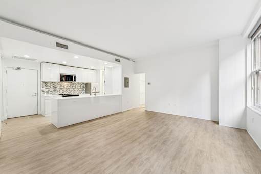 A spacious, empty room with a kitchen area in the background.