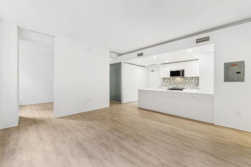 A white room with a wooden floor and a white counter.