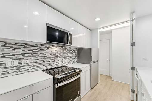 A modern kitchen with a black and white tiled backsplash and stainless steel appliances.