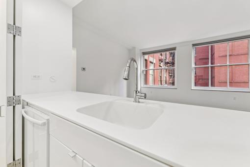 A white sink in a white bathroom with a window.