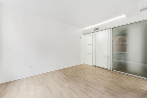 A room with a sliding glass door and wood flooring.