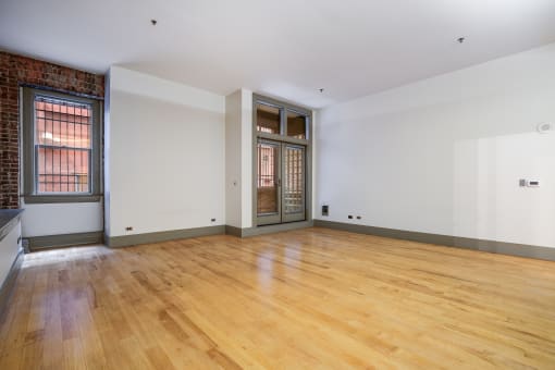a living room with white walls and wood floors and a doorway