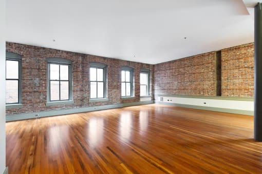 an empty room with brick walls and wood floors
