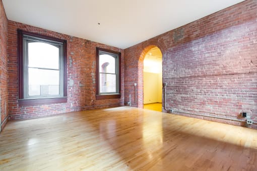 an empty living room with brick walls and wood floors