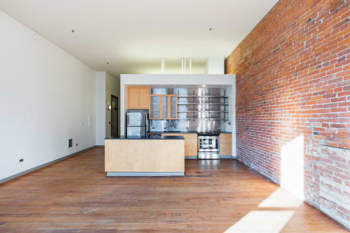a living room with a kitchen and a brick wall