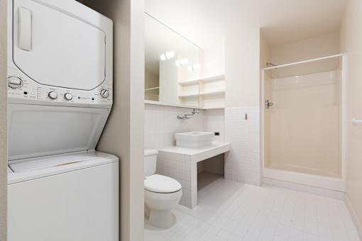 a bathroom with a washer and dryer in it and a sink and toilet