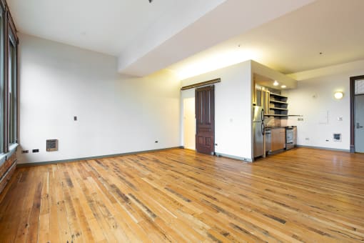 a large living room with wood floors and a kitchen