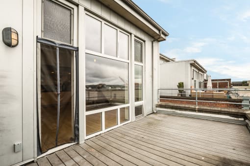 a large balcony with glass doors and a view of a train