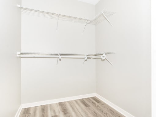 an empty closet with white walls and wood flooring and a white walled closet