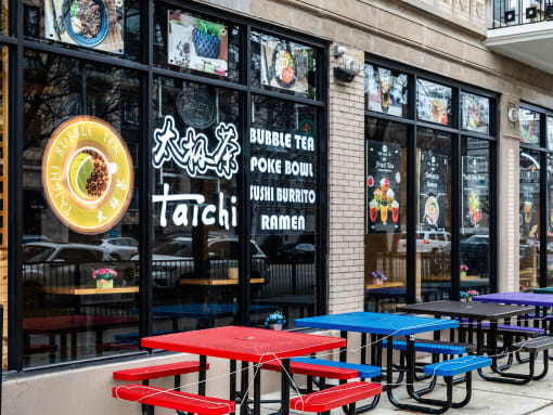 the exterior of a restaurant with red and blue tables