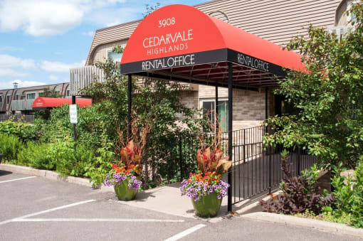 Front entrance of Eagan, MN apartment community, Cedarvale Highlands. Surrounded by professional landscaping and rustic brick facade.