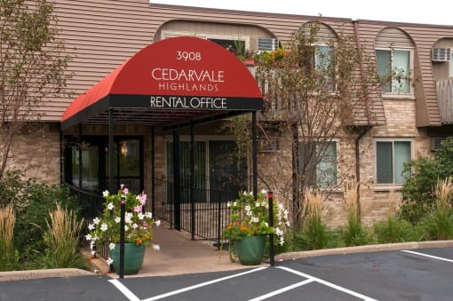Secondary view of front entrance of apartment complex, with professional landscaping and brick facade. 