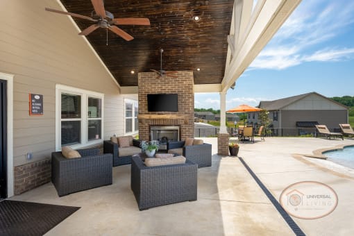 an outdoor living area with a fireplace and a ceiling fan