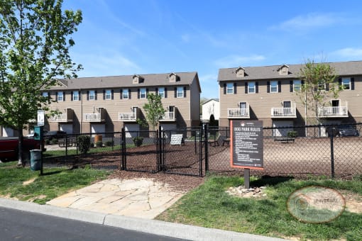 A fenced in dog park with seating and obstacles for your pet.