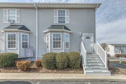 A two-story house with a grey exterior and a white door.