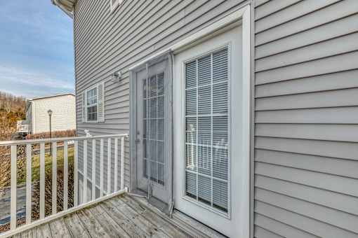 A house with a grey siding and a white door with a window above it.