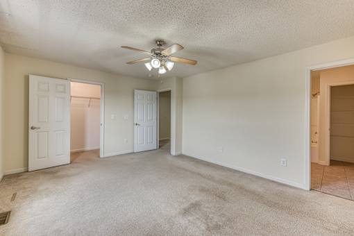 A spacious room with a ceiling fan and carpeted floor.