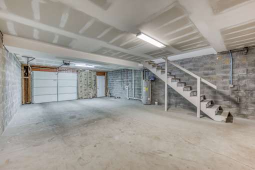 A spacious basement with a staircase and a garage door.