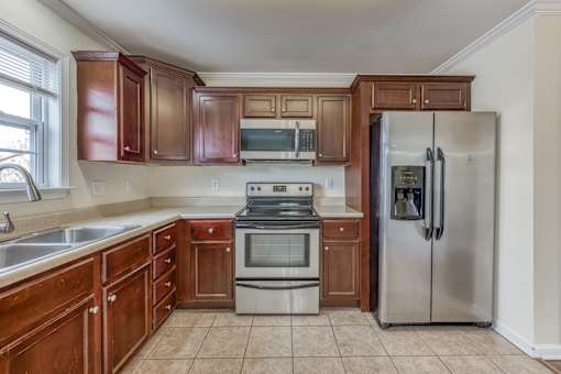 A kitchen with wooden cabinets and a stainless steel refrigerator.