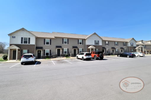 a parking lot with cars in front of a large apartment building