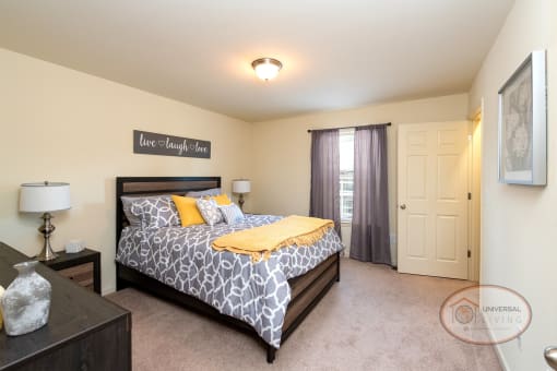 A bedroom with a large bed, dresser, carpet, and white walls.
