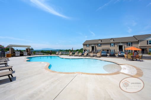 A resort style, saltwater, zero-entry pool with lounge chairs, tables with umbrellas, and a grilling station.