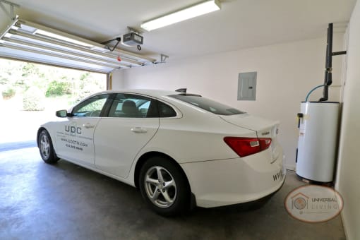 Interior of a garage with a white sedan inside.