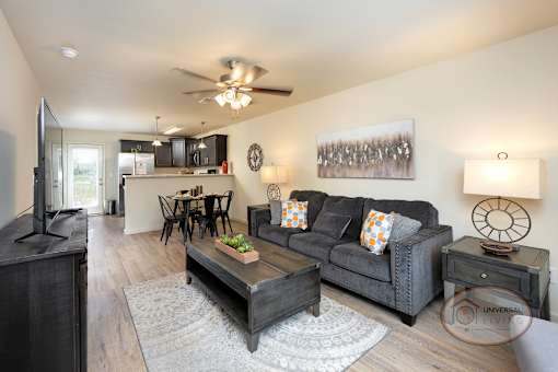 A living room with a grey couch, a coffee table, and a ceiling fan.
