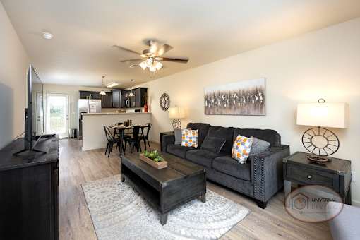 A living room with a black couch and a ceiling fan.